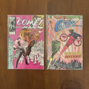 May include: Two comic books are shown. The first, "The Comet Man," has a fiery character on a pink cover. The second, "Gizmo," depicts a superhero in red and black with the text "In Blazing Battle With Inferno!"