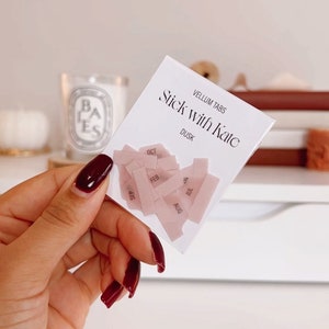 Peut inclure: Gros plan sur un paquet d'onglets en vélin étiquetés "Vellum Tabs Stick with Kate Dusk". Les onglets sont roses et portent les mois de l'année.