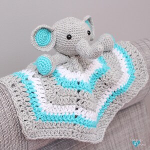 May include: A gray crocheted elephant with turquoise ears and a white and turquoise striped blanket. The blanket has a crocheted border.
