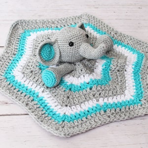May include: A gray and white crocheted baby blanket with a gray crocheted elephant attached. The blanket has a turquoise border.