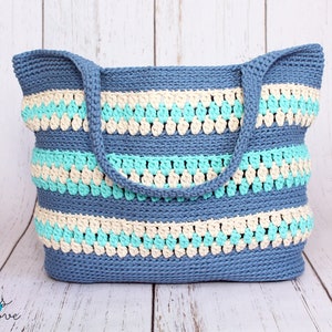 May include: A blue, beige, and turquoise crocheted tote bag with a striped pattern. The bag has two handles.