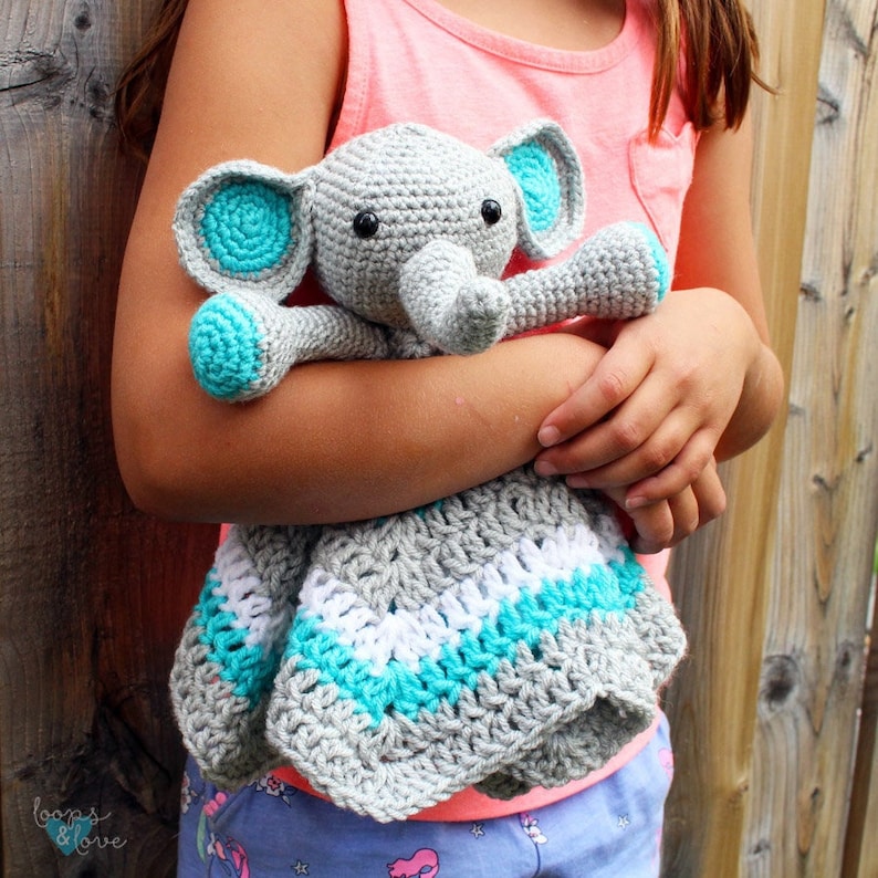 May include: A gray crocheted elephant with turquoise ears and a white and turquoise striped blanket.