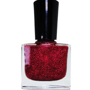 May include: A clear glass bottle of red glitter nail polish with a black cap.