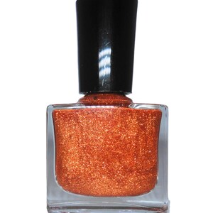 K&ouml;nnte beinhalten: Eine Flasche kupferfarbener Nagellack mit schwarzem Deckel. Der Lack hat einen glitzernden Finish.