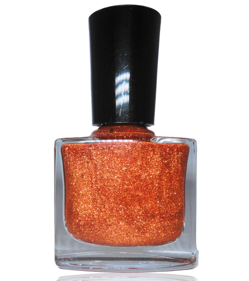 K&ouml;nnte beinhalten: Eine Flasche kupferfarbener Nagellack mit schwarzem Deckel. Der Lack hat einen glitzernden Finish.