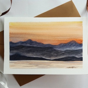 Cartão pintado à mão com envelope. Pintura em aquarela da paisagem das montanhas do pôr do sol.