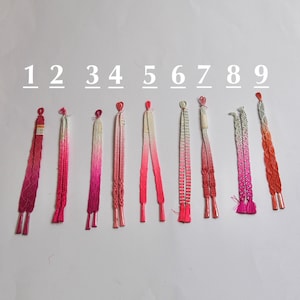 Könnte beinhalten: Neun Paar rosa und weiße Schnürsenkel mit verschiedenen Mustern und Texturen. Die Schnürsenkel sind von 1 bis 9 nummeriert.