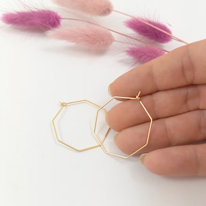 Könnte beinhalten: Ein Paar goldene achteckige Creolen. Die Ohrringe sind schlicht und elegant und würden eine großartige Ergänzung für jede Schmucksammlung sein.