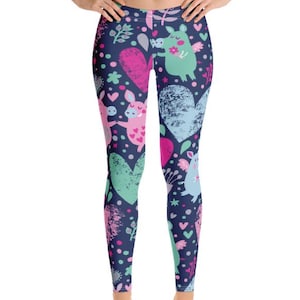May include: Full-length leggings featuring a dark blue background with a repeating pattern of pink and light blue winged pigs, textured hearts in various shades of pink, blue, and green, along with small stars, dots, and floral elements.