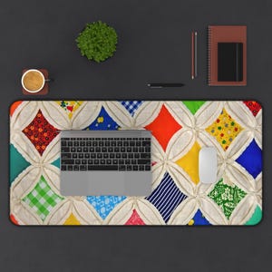 Może przedstawiać: Kolorowa podkładka na biurko z wzorem patchworkowej kołdry. Podkładka ma różne wzory tkanin w kolorach czerwonym, niebieskim, żółtym i zielonym. Na niej znajduje się laptop, mysz, filiżanka kawy i notatnik.