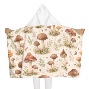 May include: A white ceramic mug with a black handle and the text "But First, Coffee" in a bold, black font. The mug is set against a blurred background. The mug appears to be approximately 10 cm tall.