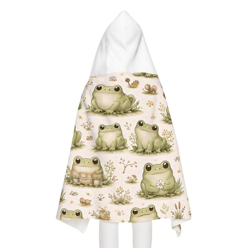 Peut inclure: Une serviette &agrave; capuche pour b&eacute;b&eacute; avec un motif de grenouilles vert clair sur fond cr&egrave;me, orn&eacute; de motifs floraux et v&eacute;g&eacute;taux. La serviette a une capuche blanche. Illustration de style enfantin.