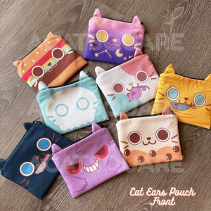 May include: Eight colourful zippered pouches, each with cat ear accents. The pouches feature various designs, including a burger, a starry night, a skull, a cat with a fish, and a boba tea design. The text "Cat Ears Pouch Front" is visible.