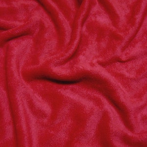 May include: A close-up of a soft, red fleece fabric. The fabric is wrinkled and has a fuzzy texture.
