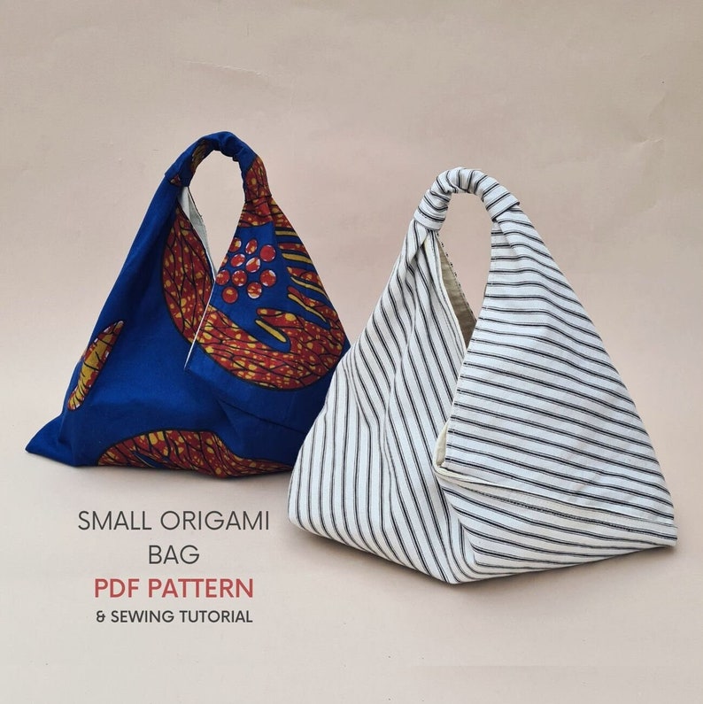 May include: Two origami bags, one with a blue and red patterned fabric and the other with white and black stripes. The bags are folded into a triangular shape with a handle at the top. The text "SMALL ORIGAMI BAG PDF PATTERN & SEWING TUTORIAL" is printed below the bags.