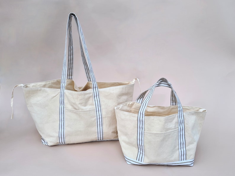 Peut inclure: Deux sacs cabas en toile avec des anses ray&eacute;es bleu et blanc. Le plus grand sac a une seule poche sur le devant. Le plus petit sac a une seule poche sur le devant.