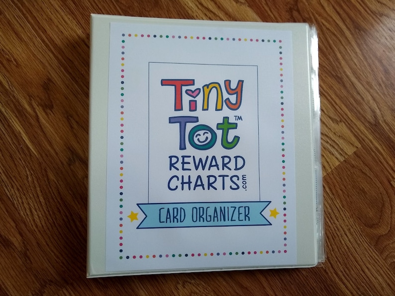 May include: White binder with a colorful border and the text "Tiny Tot&trade; Reward Charts.com Card Organizer" in the center.