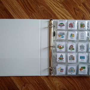 May include: A white binder with clear plastic pockets containing colorful illustrations of various places and activities. The illustrations include a library, farm, farmer's market, housing, rec center, shopping, eye doctor, bank, camping, cabin, museum, cruise, indoor playground, hardware store, aquarium, toy store, post office, mall, friends, and a nature center.