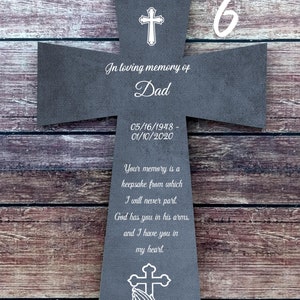 Peut inclure: Une croix en bois gris avec un motif de croix blanche et de mains en prière. La croix porte le texte "In loving memory of Dad 05/16/1948 - 01/10/2020" et "Your memory is a keepsake from which I will never part. God has you in his arms, and I have you in my heart."