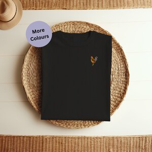 May include: Black t-shirt with a small embroidered rooster design on the left chest. The rooster is brown, yellow, and red.