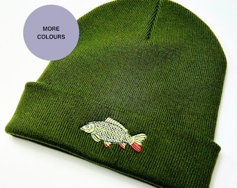 Pode incluir: Um gorro de malha verde com um design de peixe-carpa bordado. O gorro tem uma aba.
