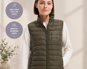 Puede incluir: Chaleco acolchado verde oliva con cuello alto y cremallera completa. El chaleco tiene un logotipo cuadrado blanco que dice "THREAD AND NEEDLES CO". La imagen también incluye dos círculos morados con el texto "ADD YOUR TEXT OR LOGO" y "MENS & WOMENS SIZES".