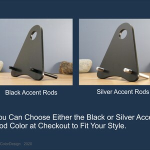May include: Two black metal phone stands with a triangular design and a circular hole at the top. One stand has black accent rods, the other has silver accent rods. The text reads: "You Can Choose Either the Black or Silver Accent Rod Color at Checkout to Fit Your Style."