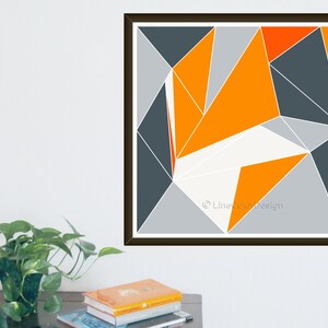 May include: Abstract geometric print with a design of triangles in orange, grey, and white. The artwork is set against a white background and framed in a dark brown frame. The print is signed "LineColorDesign".