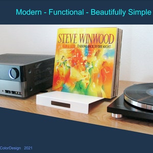 May include: A white vinyl record holder with a black turntable and stereo equipment. The album cover for Steve Winwood's "Talking Back to the Night" is displayed. The text "Modern - Functional - Beautifully Simple" is at the top.