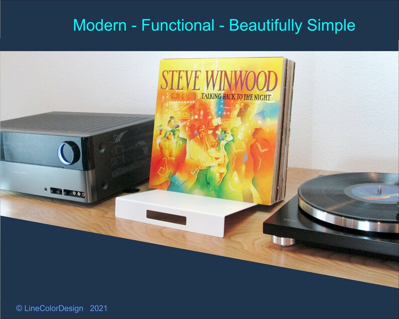 May include: A white vinyl record holder with a black turntable and stereo equipment. The album cover for Steve Winwood's "Talking Back to the Night" is displayed. The text "Modern - Functional - Beautifully Simple" is at the top.