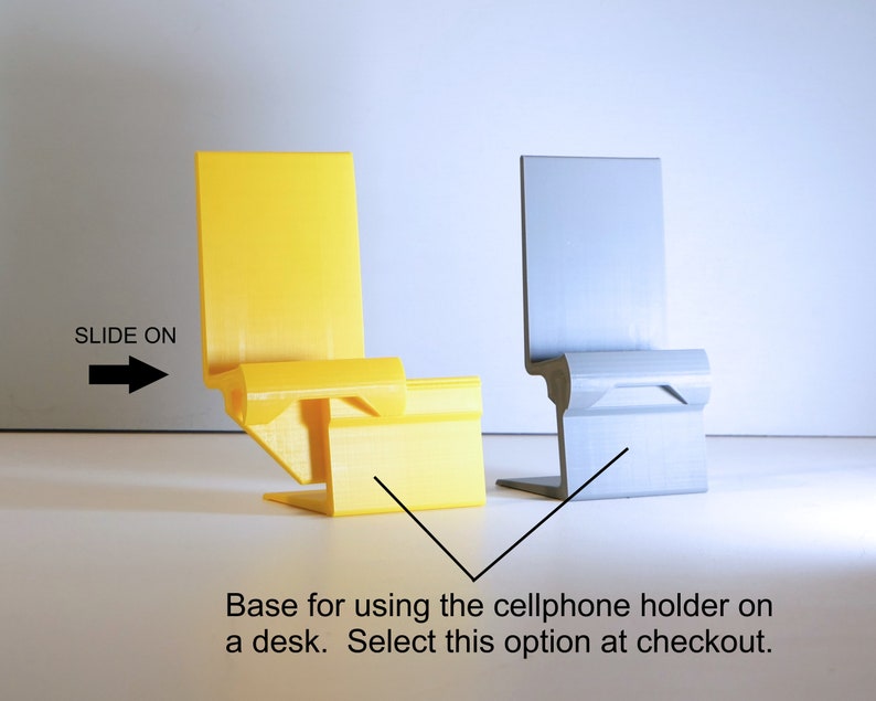 K&ouml;nnte beinhalten: Zwei minimalistische Handyhalter, einer gelb und einer grau, werden gezeigt. Der gelbe Halter befindet sich links und der graue rechts. Der Text "SLIDE ON" und ein Pfeil befinden sich links. Der Text "Base for using the cellphone holder on a desk. Select this option at checkout." befindet sich unten.