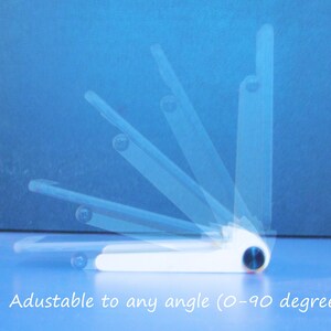 May include: White adjustable phone stand with a blue accent, shown at various angles against a blue background. The stand is designed to adjust from 0 to 90 degrees. Text on the image reads: "Adustable to any angle (0-90 degrees)".