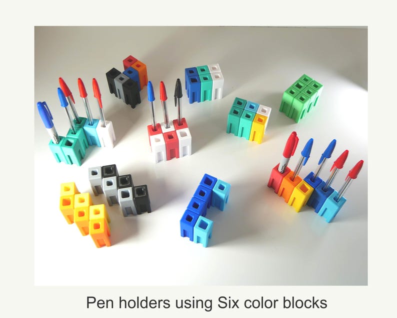 May include: A collection of colorful pen holders made from interlocking blocks. Each holder is a different color, including red, orange, yellow, green, blue, and white. The holders are filled with pens with red and blue ink. The text at the bottom reads: Pen holders using Six color blocks.