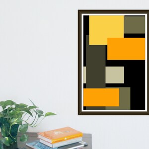 May include: Abstract art print featuring a geometric design with overlapping rectangles in yellow, orange, gray, and black. The artwork is framed in a dark brown frame and is displayed on a white wall.