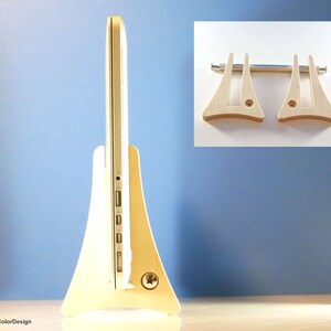 May include: A light-coloured wooden laptop stand with a minimalist design. The stand supports a silver laptop. The stand has a wide base and a curved shape, with a small inset for the laptop's ports. An inset image shows two additional stand pieces.