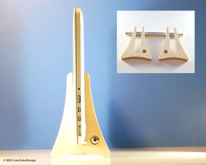 May include: A light-coloured wooden laptop stand with a minimalist design. The stand supports a silver laptop. The stand has a wide base and a curved shape, with a small inset for the laptop's ports. An inset image shows two additional stand pieces.