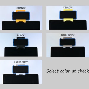 May include: A product display featuring five color options: orange, yellow, black, dark grey, and light grey. Each option showcases a phone held by a stand on top of a black surface. The text "Select color at checkout" is also visible.