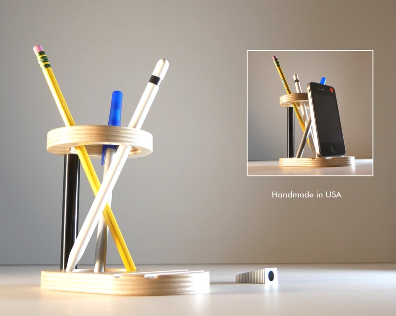 May include: A wooden desk organizer with a circular pen and pencil holder and a rectangular base. The organizer holds pencils, pens, and a smartphone. The text "Handmade in USA" is visible.