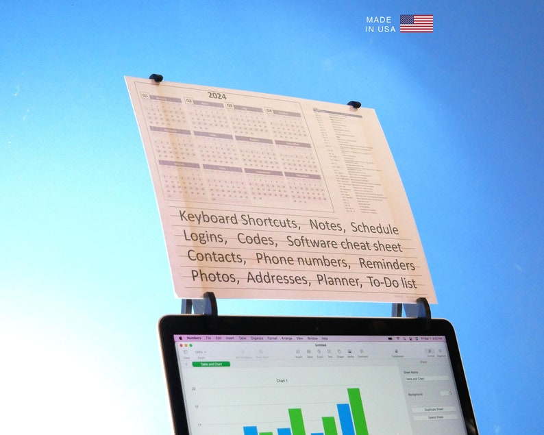 Op de afbeelding: Een wit papier met een kalender voor 2024 en een lijst met handige notities is bevestigd aan een laptop. De tekst bevat "Sneltoetsen, Notities, Schema, Logins, Codes, Software cheat sheet, Contacten, Telefoonnummers, Herinneringen, Foto's, Adressen, Planner, To-Do lijst". De Amerikaanse vlag en "MADE IN USA" staan rechtsboven.