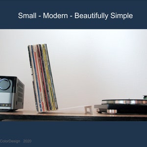 May include: A modern audio setup featuring a silver and black stereo receiver, a turntable, and a stack of vinyl records. The image includes the text "Small - Modern - Beautifully Simple."