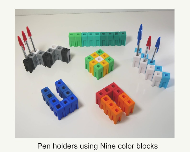 May include: A collection of colorful pen holders made from interlocking blocks. The holders are in various shapes and colors, including black, gray, white, blue, green, yellow, orange, and red. Some holders contain pens with red or blue ink. Text: Pen holders using Nine color blocks.