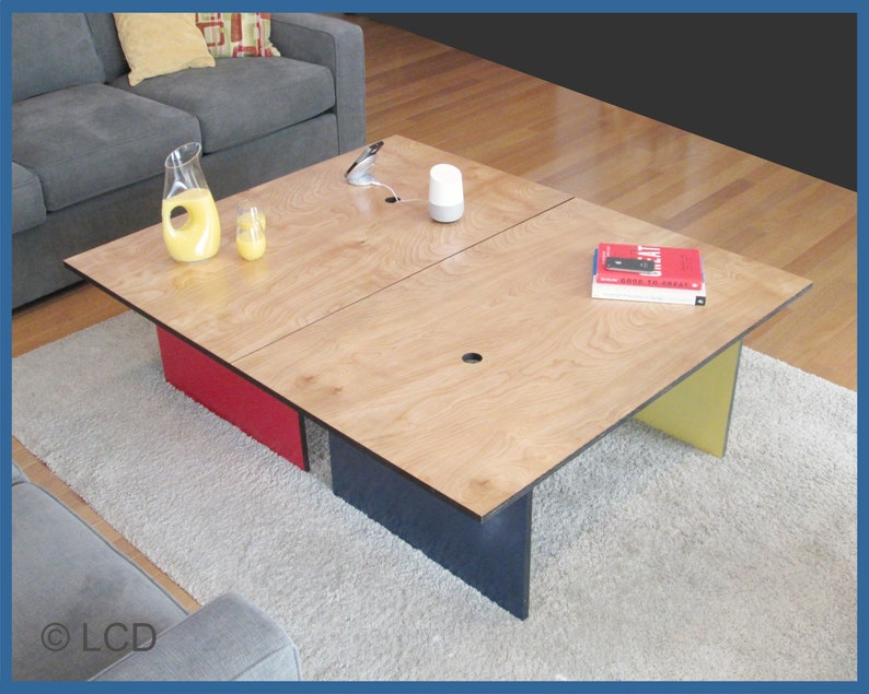 May include: A modern coffee table with a light wood grain top and colorful accents. The table has red, yellow, and navy blue supports. The table is rectangular and has a length of approximately 60 inches and a width of 30 inches.