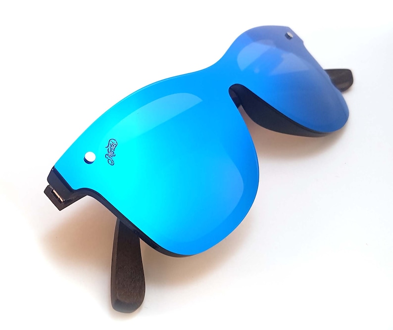 Puede incluir: Gafas de sol azules espejadas con montura de madera oscura. Las gafas tienen una forma angular &uacute;nica.