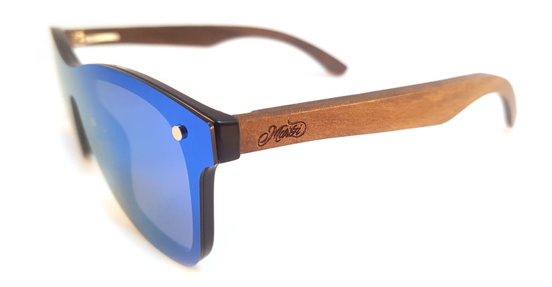 Puede incluir: Gafas de sol azules con espejo y montura de madera. La montura es marr&oacute;n y tiene la palabra "Manzi" grabada.