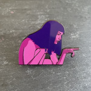 Puede incluir: Un pin de esmalte rosa con una mujer de pelo morado, mirando hacia un lado, con la mano extendida.
