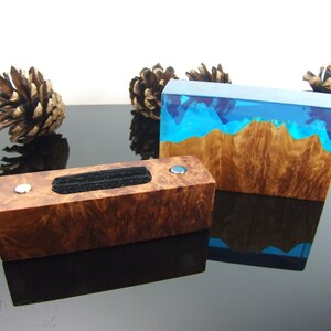 May include: Two wooden ring holders with a blue resin inlay. One holder has a black velvet ring cushion. Both holders have a natural wood grain pattern.
