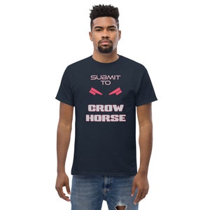 Könnte beinhalten: Ein marineblaues T-Shirt mit dem Text "SUBMIT TO CROW HORSE" in weißer und rosa Schrift. Der Text ist mit einem Paar rosa Augen über den Worten "CROW HORSE" stilisiert.