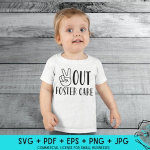 May include: A white t-shirt with a black peace sign and the text "You Out Foster Care" on it. The shirt is being worn by a young child.