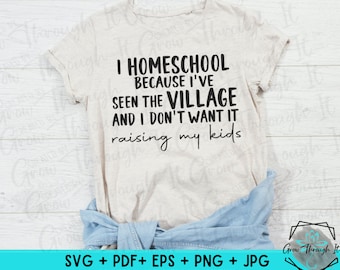 Può includere: Una maglietta beige con il testo "I homeschool because I've seen the village and I don't want it raising my kids". Il testo è in nero e la maglietta è su una superficie di legno.
