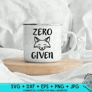 May include: A white ceramic mug with a black outline of a fox and the text "ZERO GIVEN". The mug is sitting on a wooden surface.